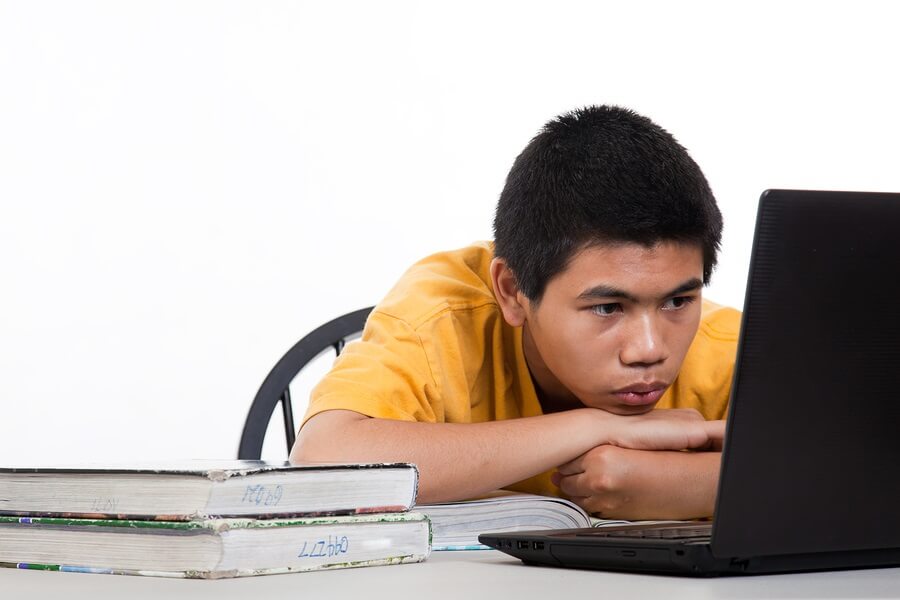 Teen boy doing homework on laptop