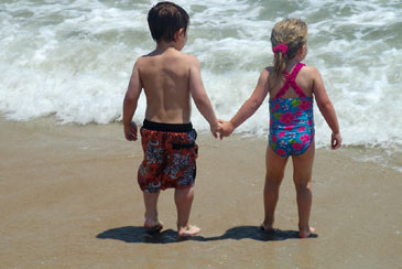 Girlandboytoddlerholdinghandsatthebeach