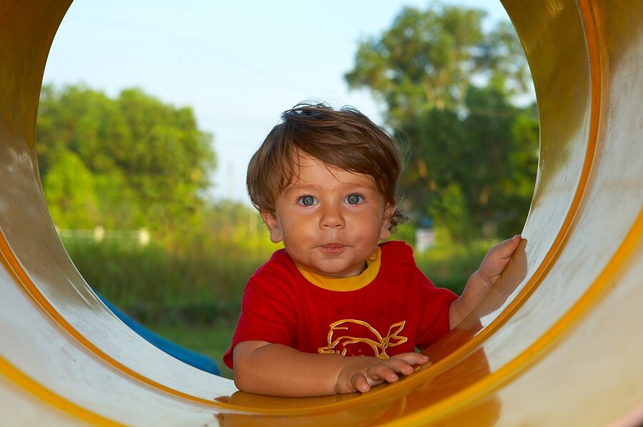 Little boy looking through tunnel at playground