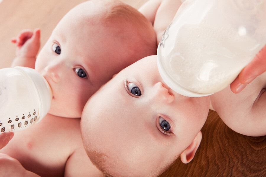 Two babies drinking bottles of formula