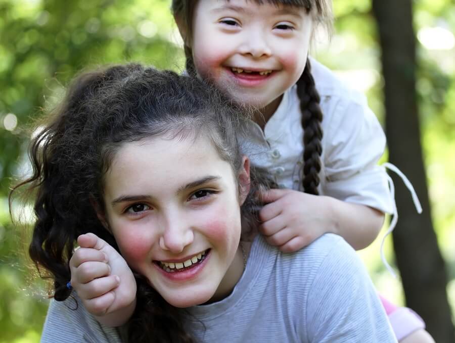 Two happy sisters with child with Down syndrome