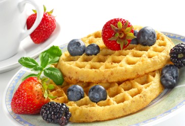 Plate of waffles and berries on table.