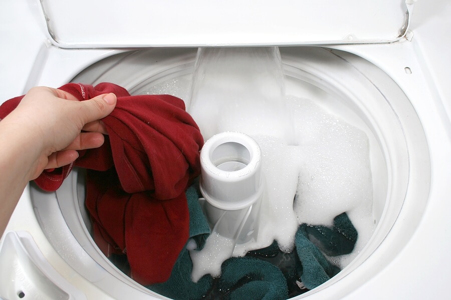 Close up of washing machine full of clothes against white back drop.