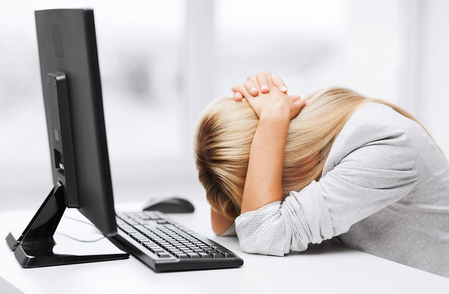 Frustrated woman with head on desk in front of computer