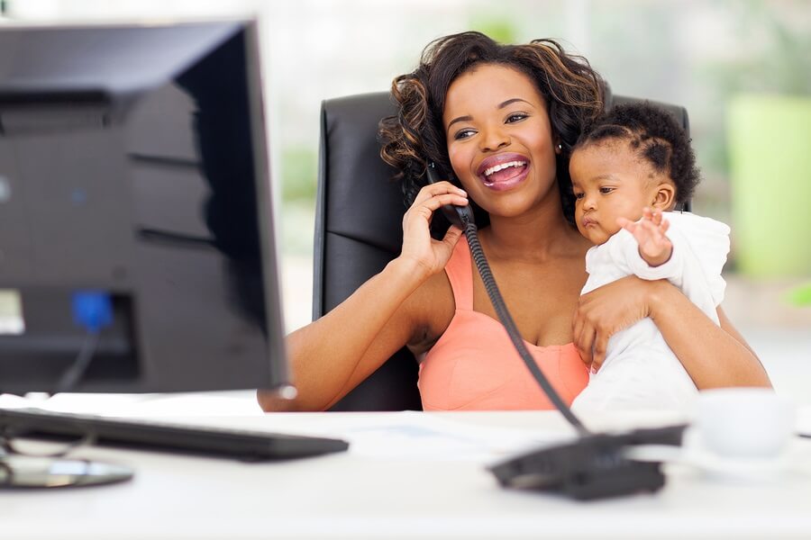 Working mom talking on phone with baby in lap.