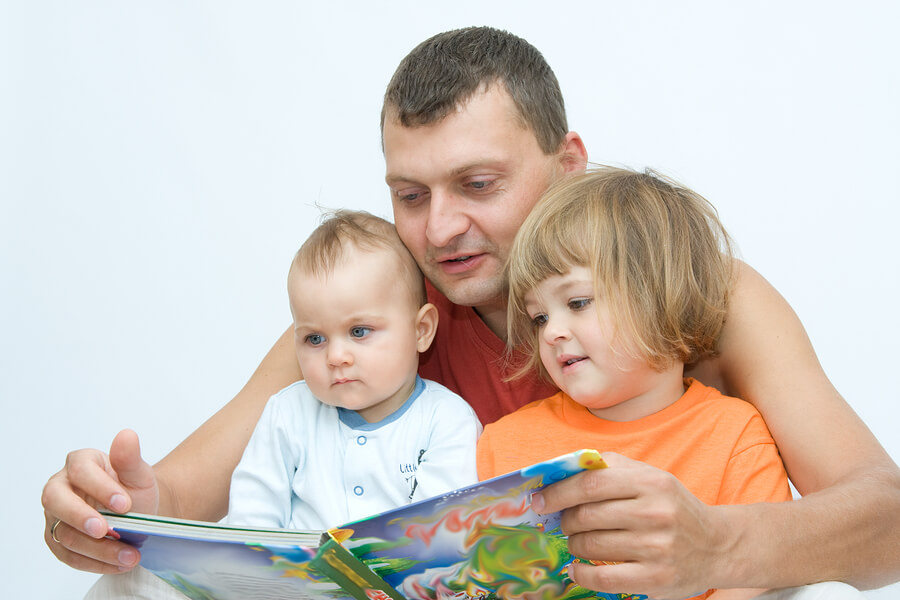 father reading to baby and toddler