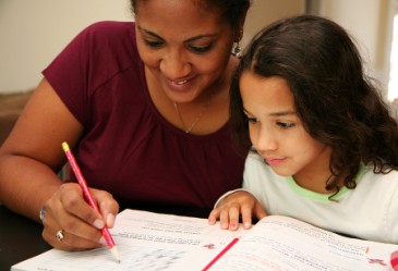 Yourng girl doing homework with her mother