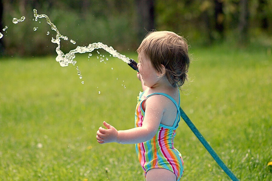 Toddler playing with garden hose outside