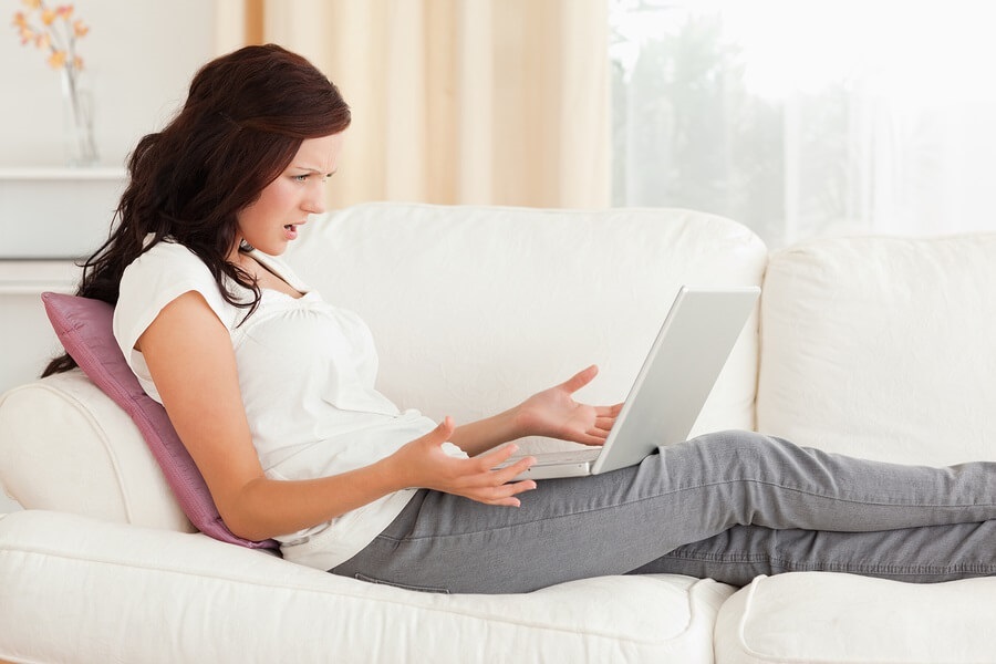 Woman sitting on couch looking annoyed on computer