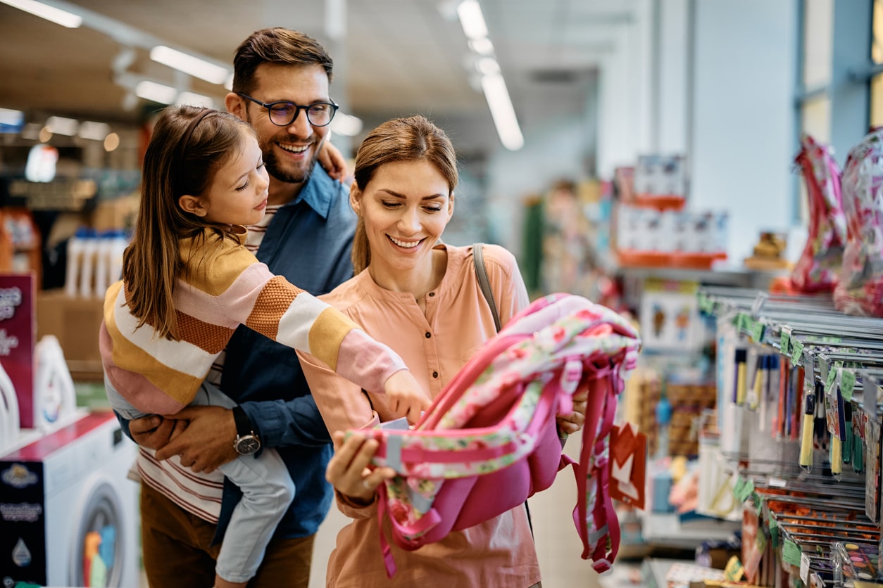 Family looks at new backpack for kindergarten daughter as they back to school shop