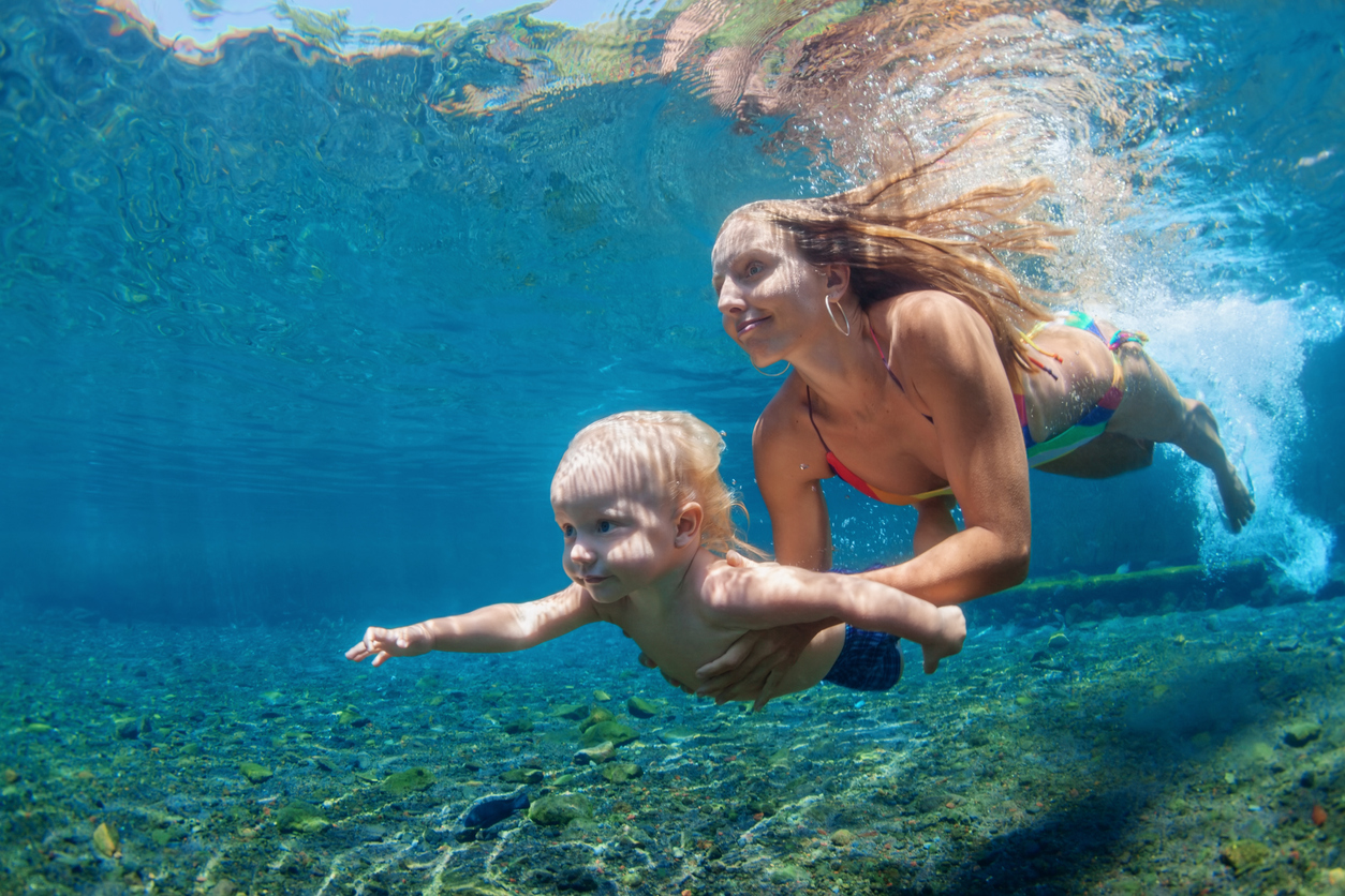 Happy family - mother with baby boy dive underwater with fun in sea pool. Healthy lifestyle, active parent, people water sport outdoor activity and swimming lessons on beach summer holidays with child