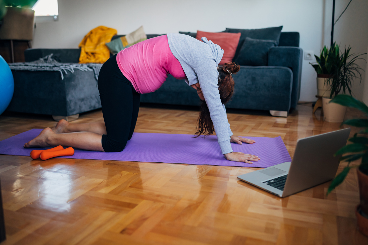 Pregnant woman doing cat/cow yoga pose to strengthen the pelvic floor region