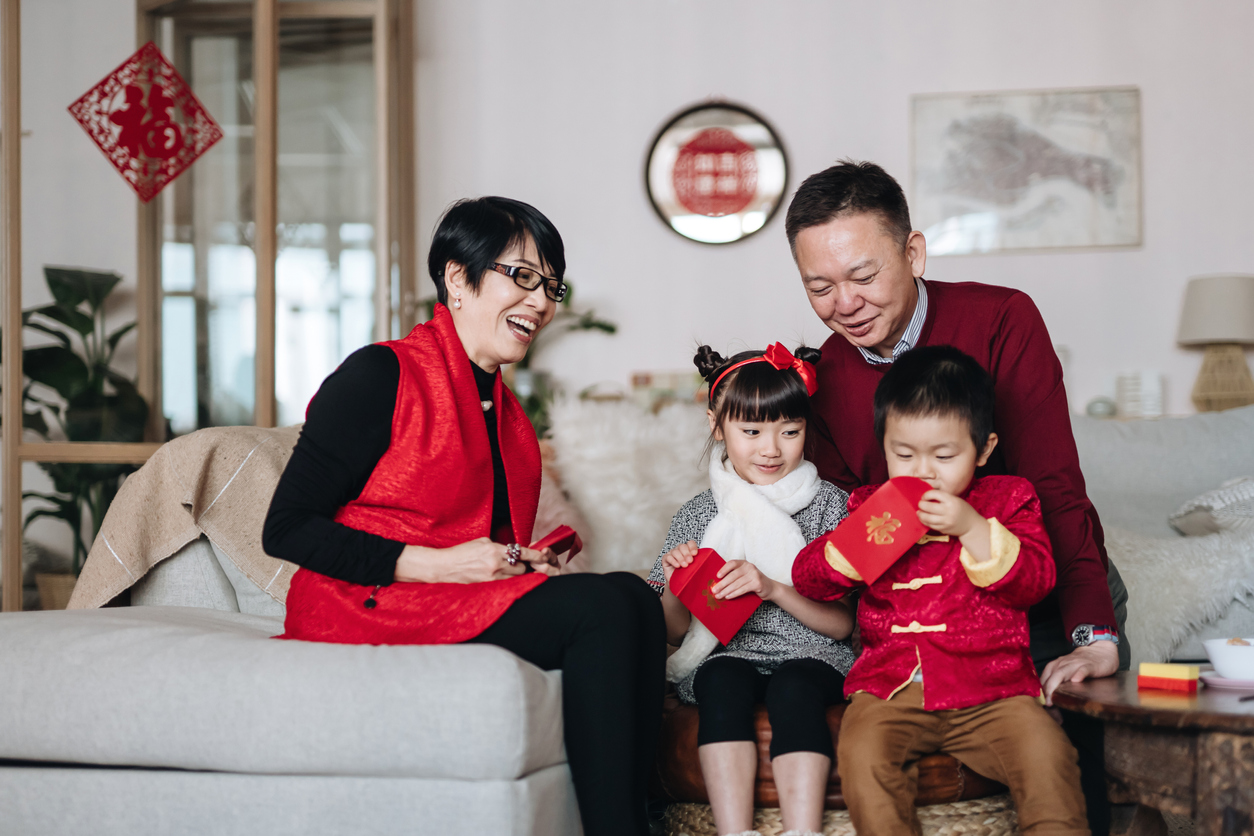 Asian-American family celebrating the Lunar New Year. Children opening red envelopes to celebrate Chinese New Year