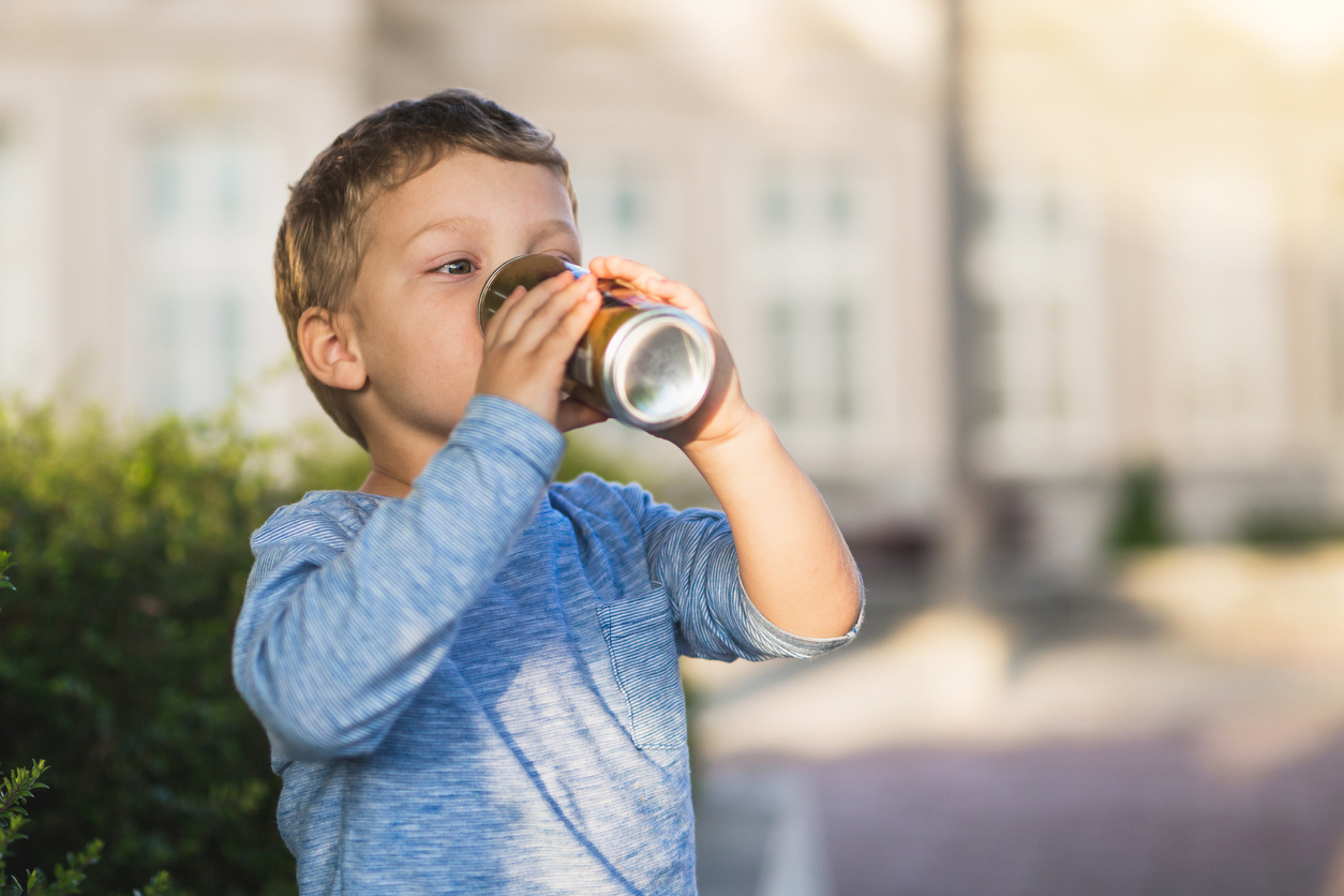 Little boy drinks soda from a can