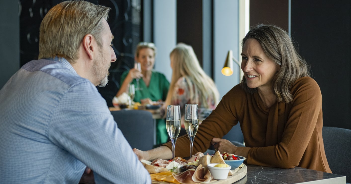 Older married couple sit in a cafe on a date, speaking to each other