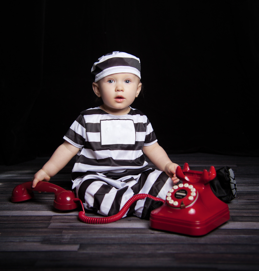 An adorable baby dressed in a prison uniform.