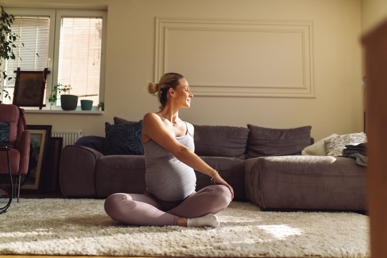 Pregnant woman practices yoga stretches at home to improve Diastasis Recti