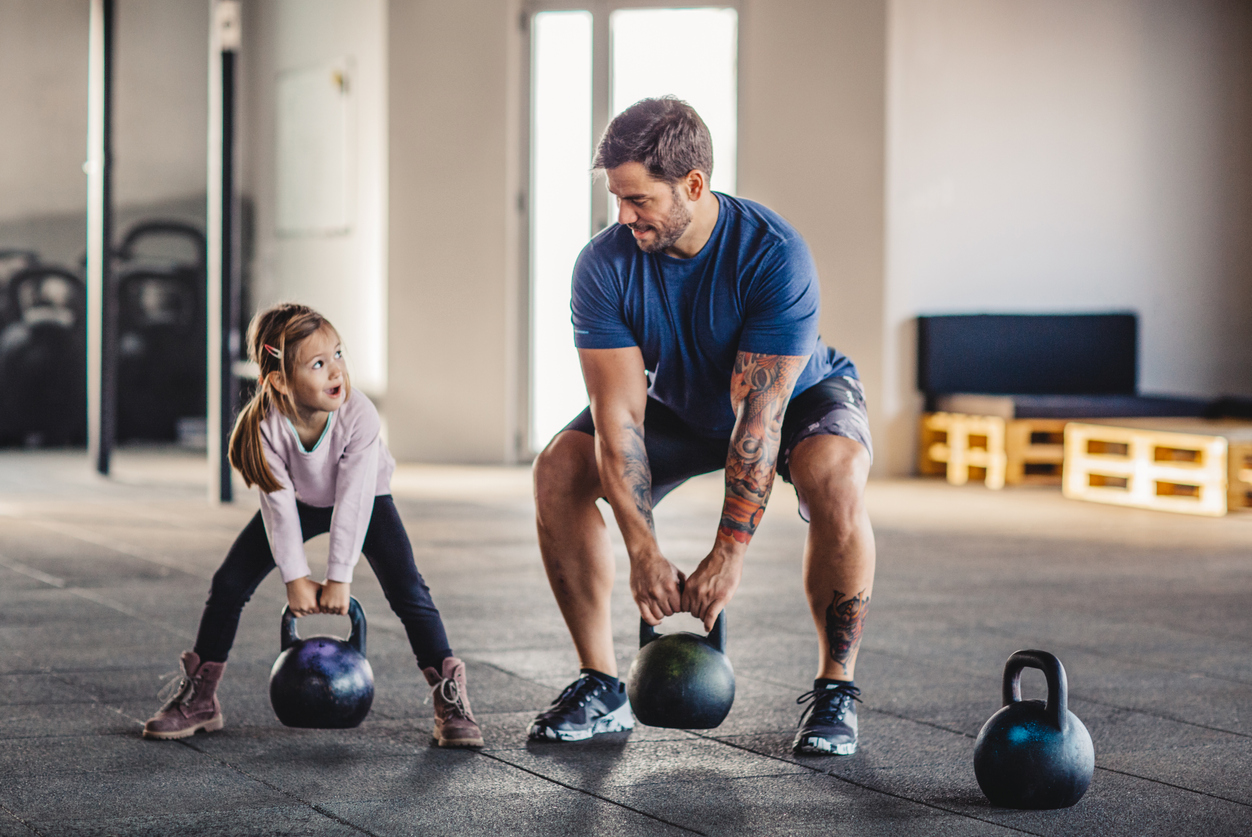 father and daughter lift weights together in the gym