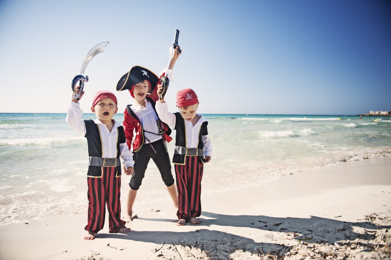 Three pirate kids celebrating on a beach. Pirate name options for your baby boy.