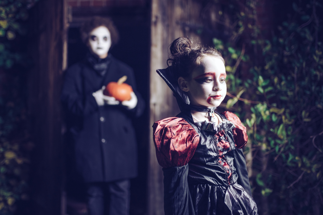 two kids in spooky halloween costumes at night in moonlight
