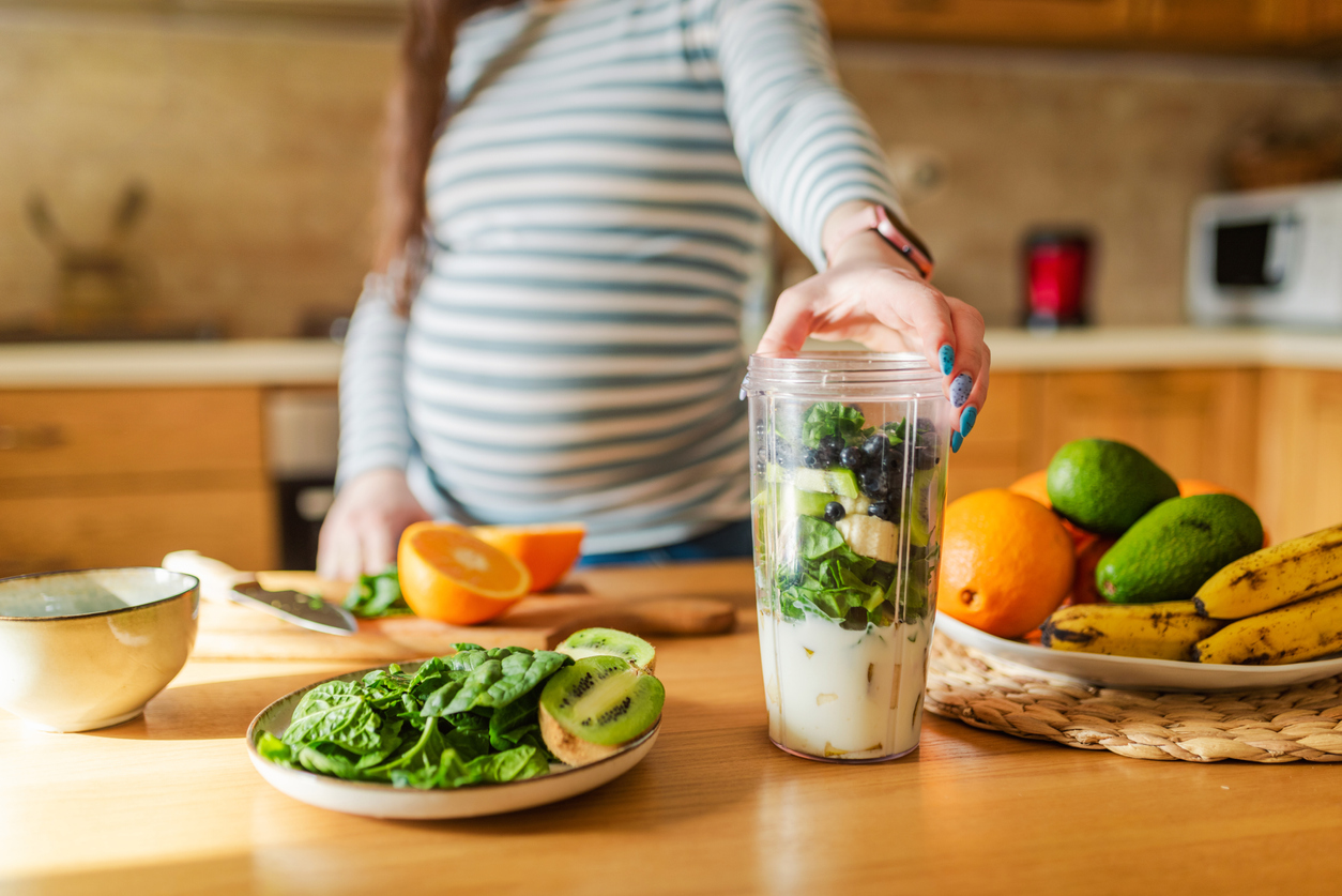 Pregnant woman making healthy smoothie.