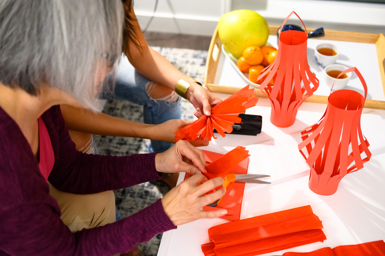 Teen and grandmother making painted Chinese paper lanterns for the Lunar New Year