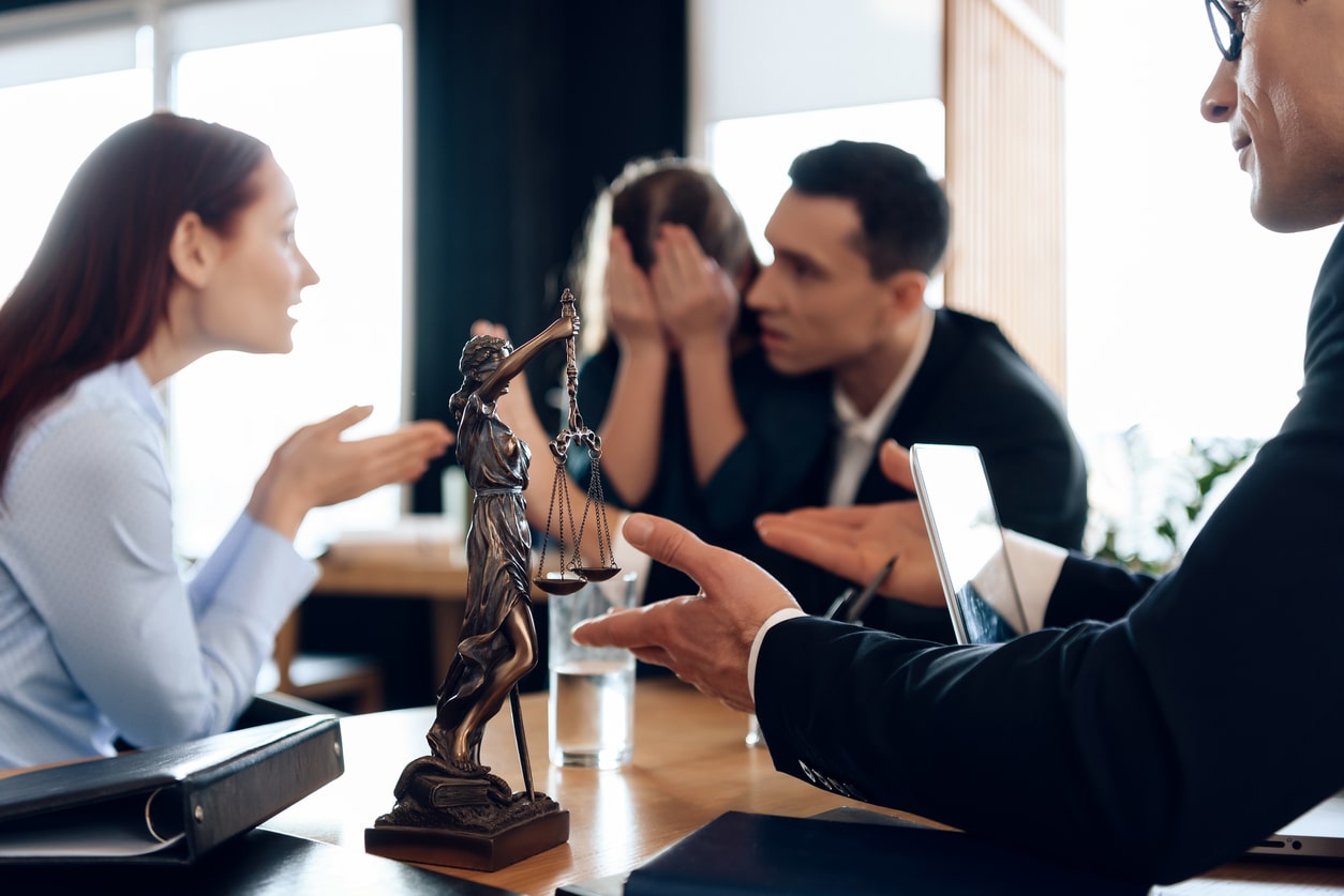 Bronze statue of Themis holds scales of justice. In unfocused background, couple divorce. Young parents argue about one who will take guardianship of little daughter in lawyer's office.