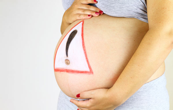 Pregnant Lady Holding Belly With Caution Sign Written on it - Down Syndrome