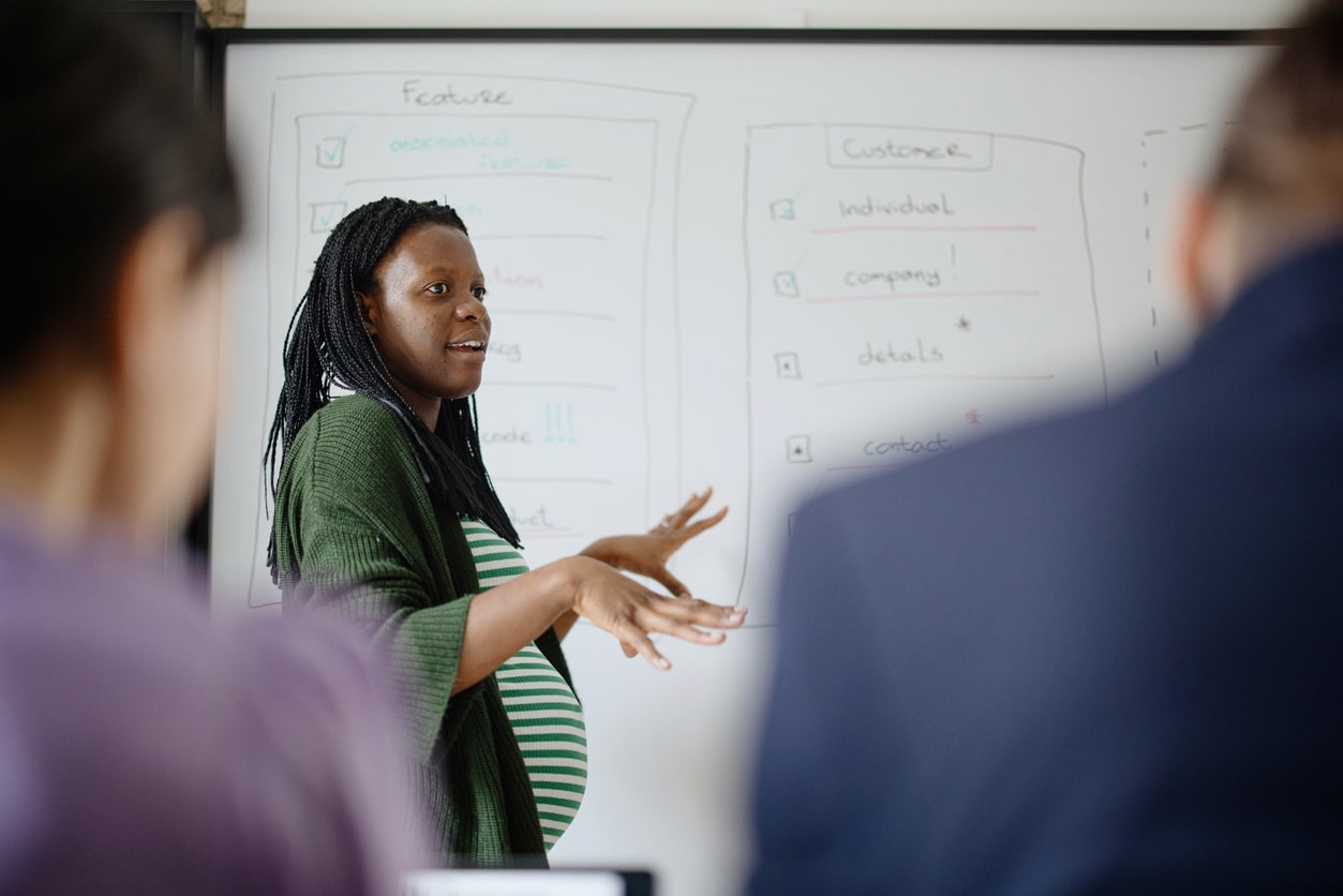 Pregnant businesswomen presenting project to coworkers in a creative working space