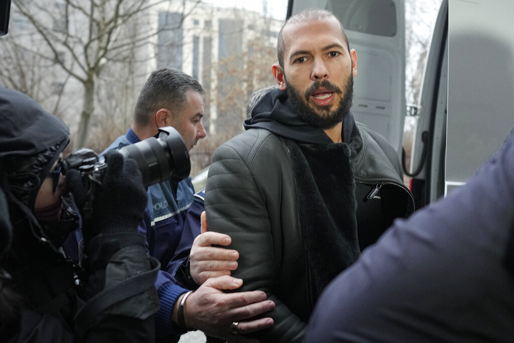 Police officers escort Andrew Tate, handcuffed to his brother Tristan, outside the Directorate for Investigating Organized Crime and Terrorism (DIICOT) where prosecutors examine electronic equipment confiscated during the investigation in their case, in Bucharest, Romania, Thursday, Jan. 26, 2023.
