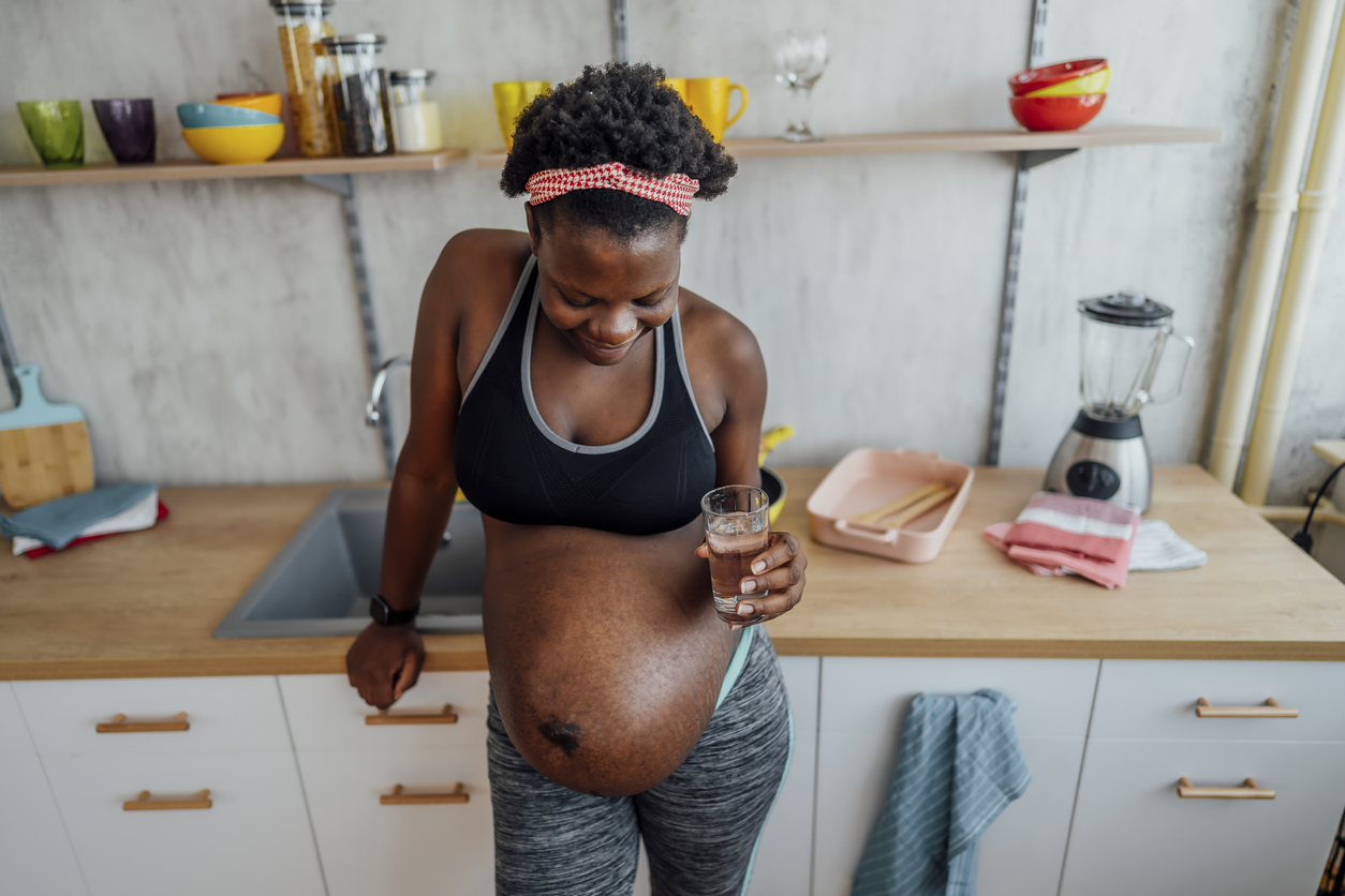 Young black pregnant woman drinking water