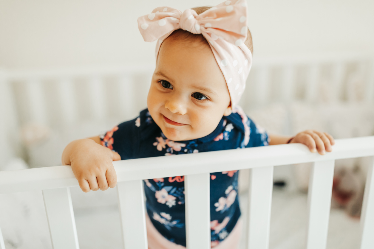 Cute baby girl standing in her crib