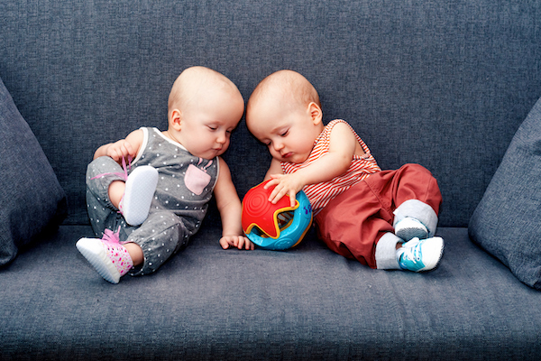 Twin babies with four-letter names playing with ball