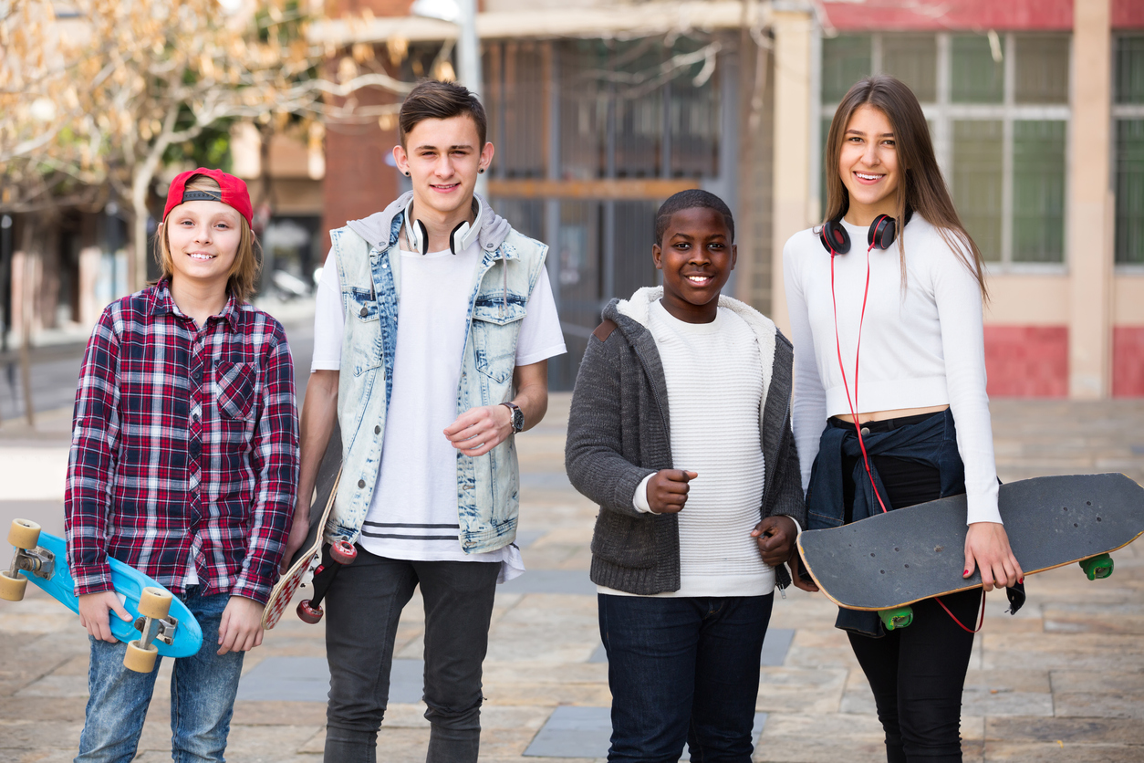 Four teens with skateboards outdoors stock photo