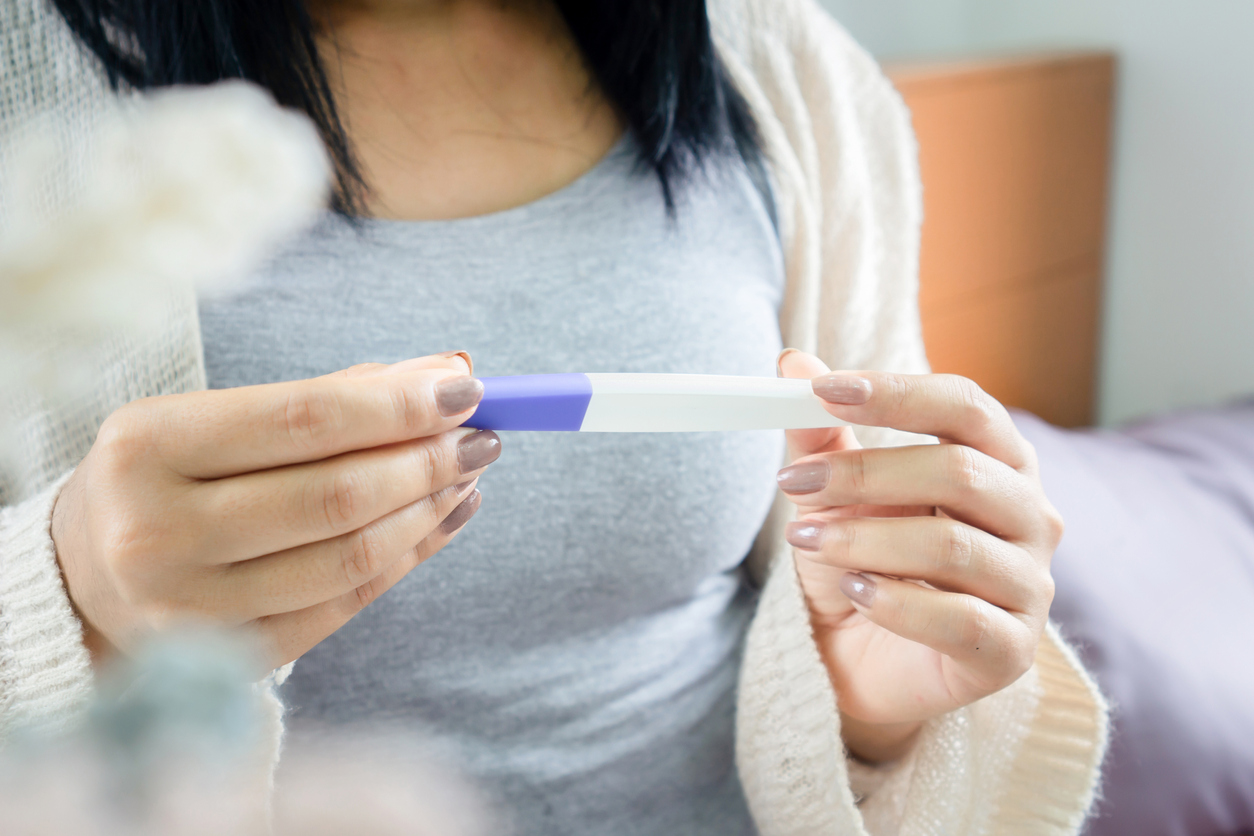 closeup woman hand holding pregnancy test looking at the positive, negative result