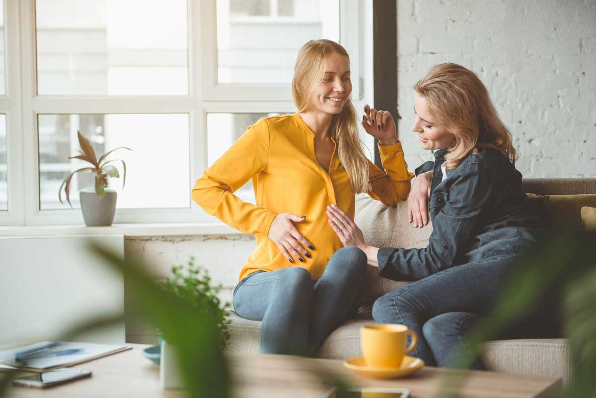 pregnant woman talking with friend on couch