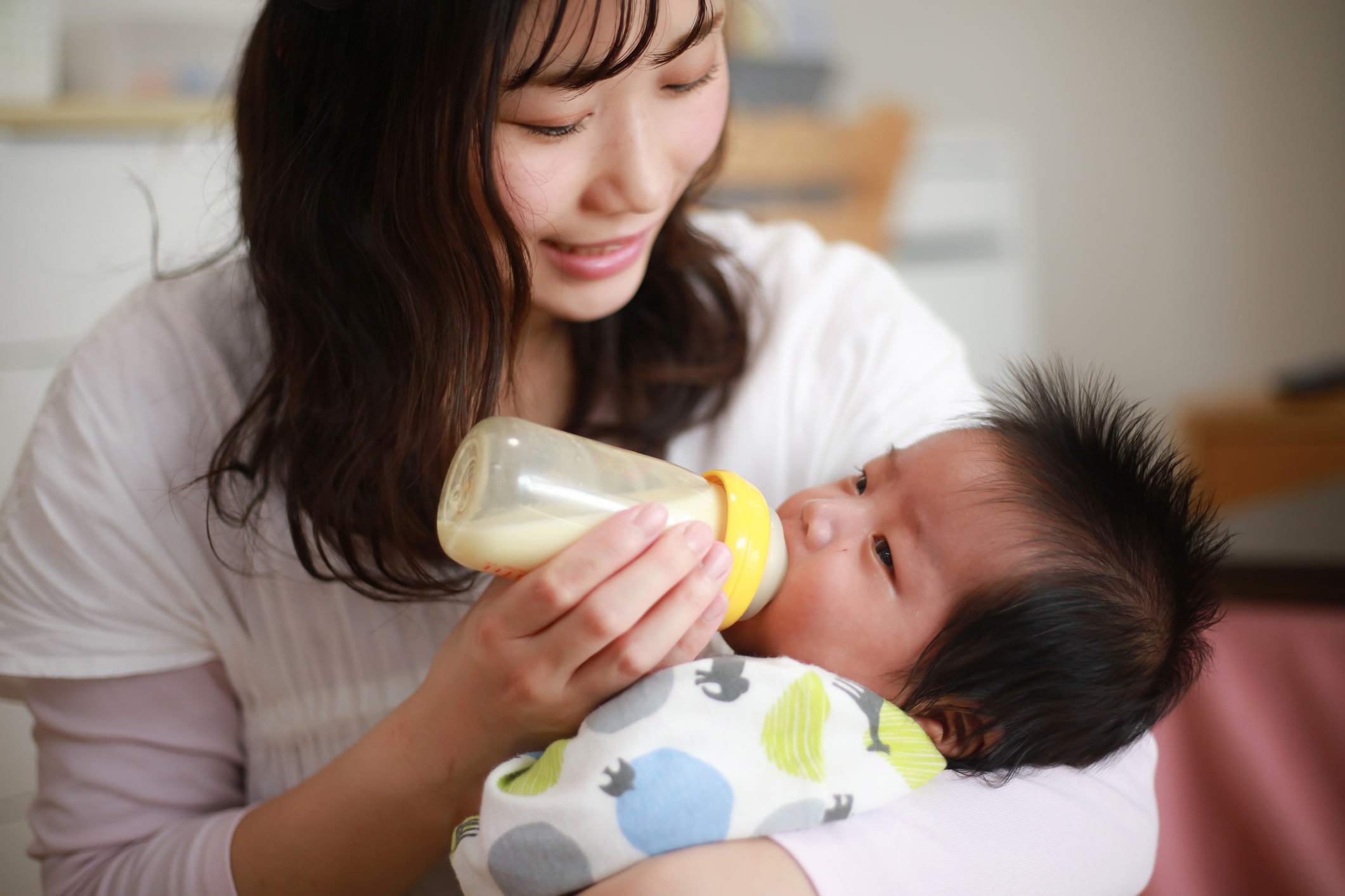 Mother feeds baby bottle. A look at the top 12 baby bottle warmers.