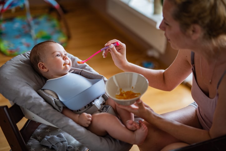 Mother feeding her smiling baby boy puree