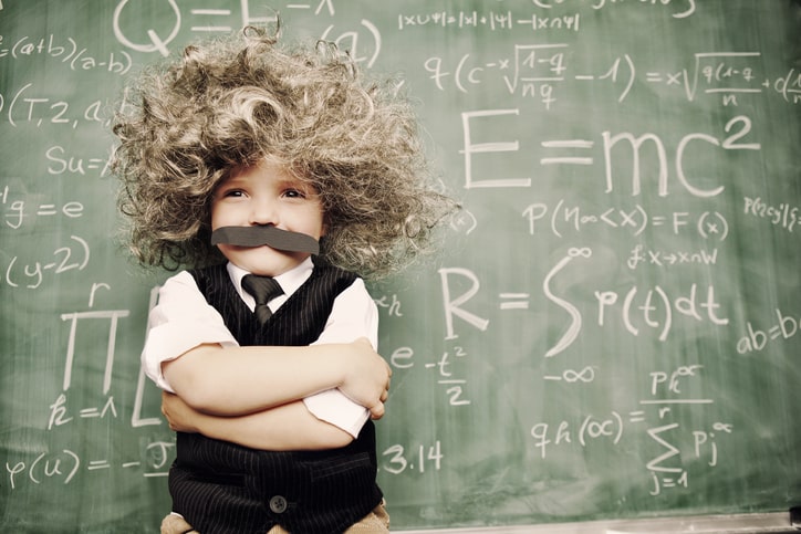 Young boy dresses as Einstein and stands in front of school blackboard