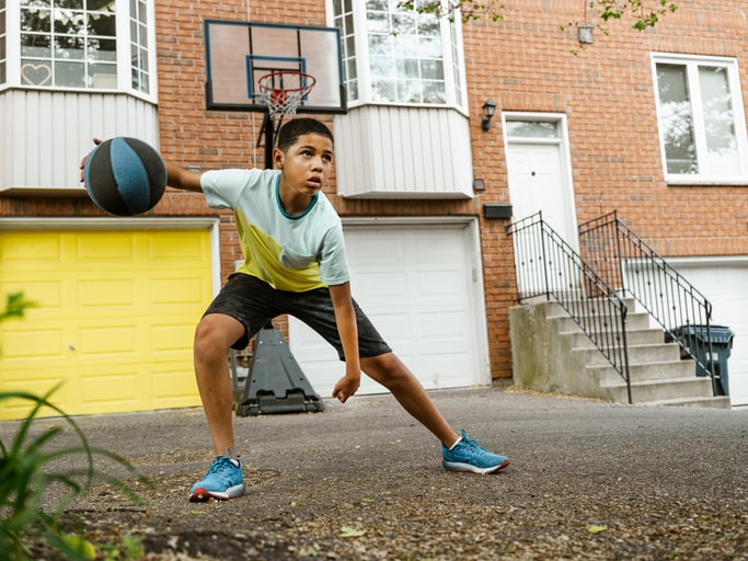 10-year-old boy plays basketball outside his house