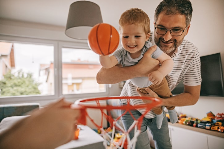 Father and son having fun, playing basketball at home
