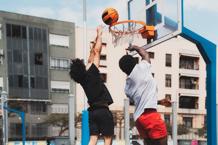 Two young boys play basketball together outside