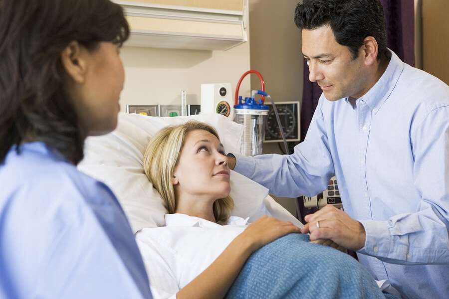 Pregnant Woman and Partner Talking to Doctor