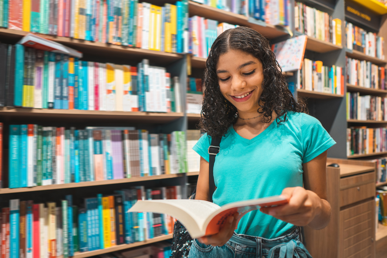 teen girl reads book in school library