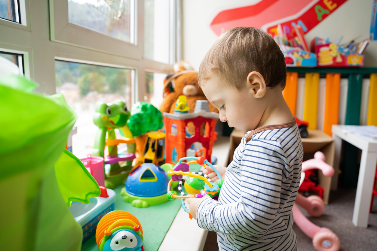Toddler boy plays with educational toys in the children's room. 