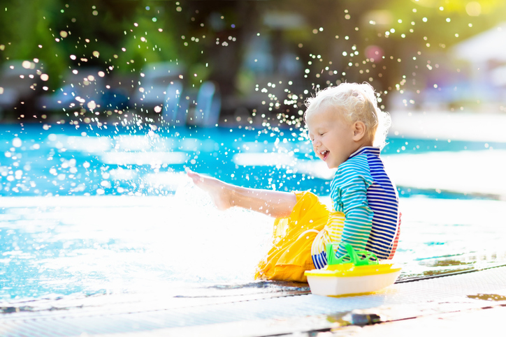 little boy splashing in pool 