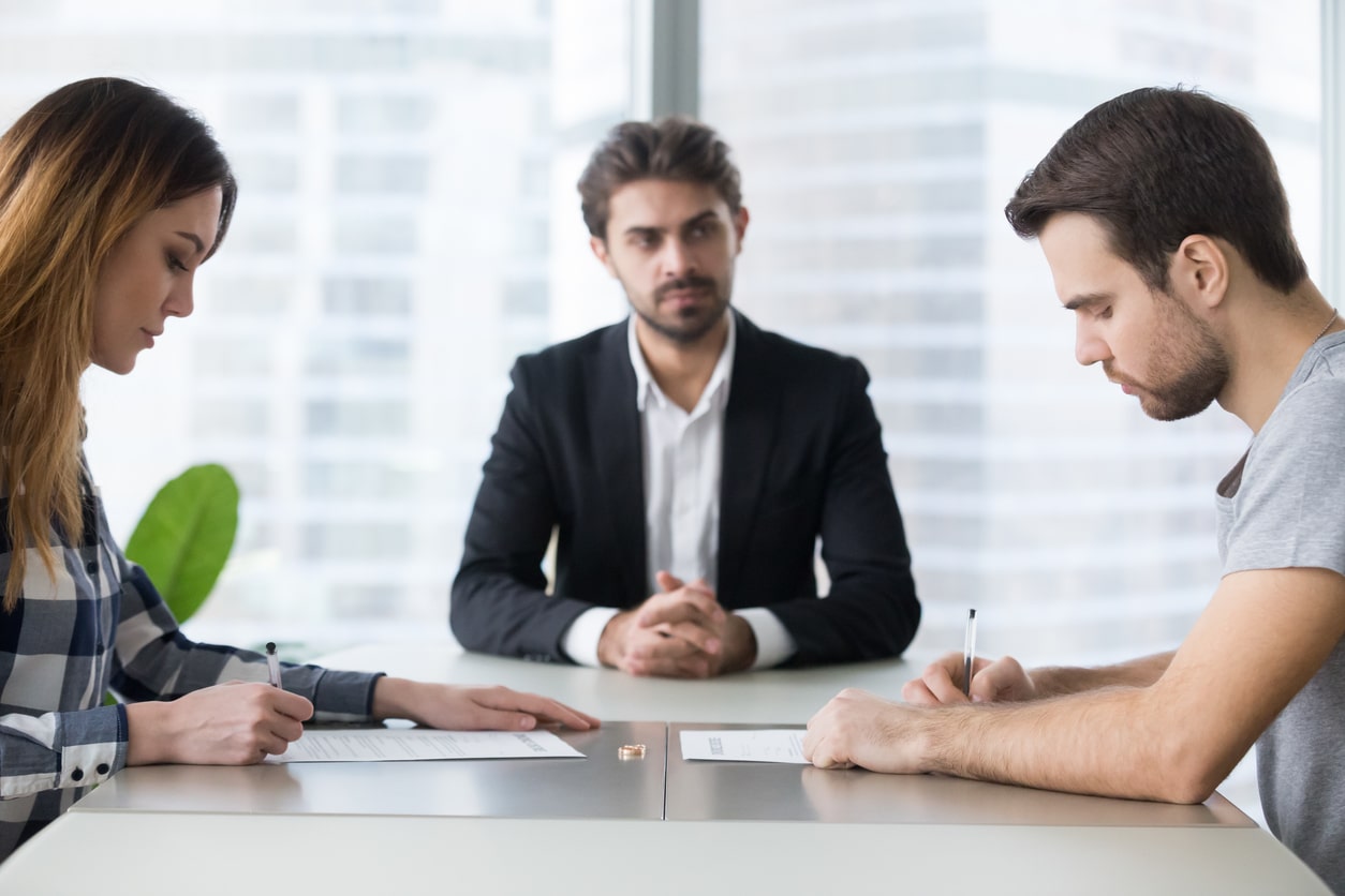 Divorced couple sits with lawyer in lawyer's office, discussing court ordered coparenting classes