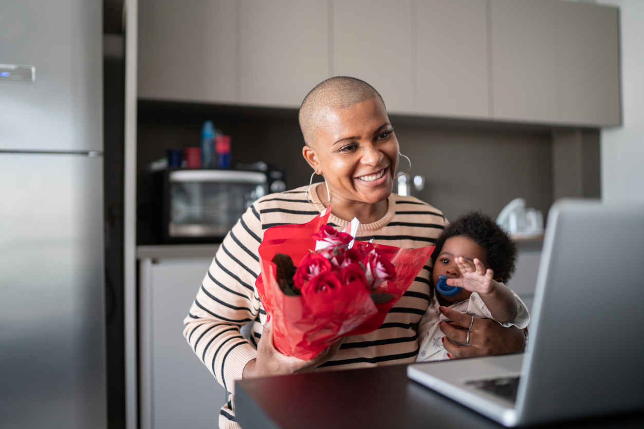 Mother with baby son receiving roses from boyfriend during video call
