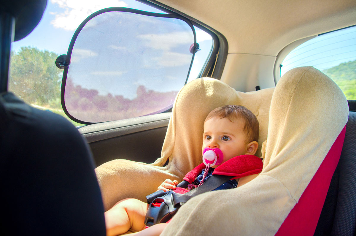 baby in carseat with sun shades on car window