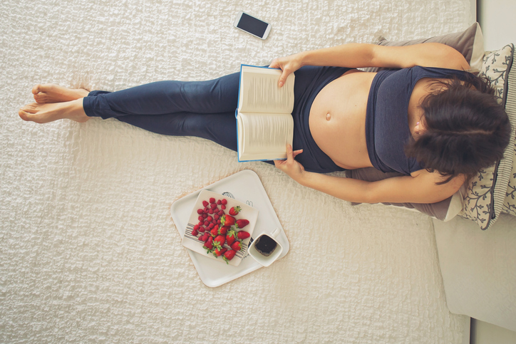 a pregnant woman in the first trimester reading a book